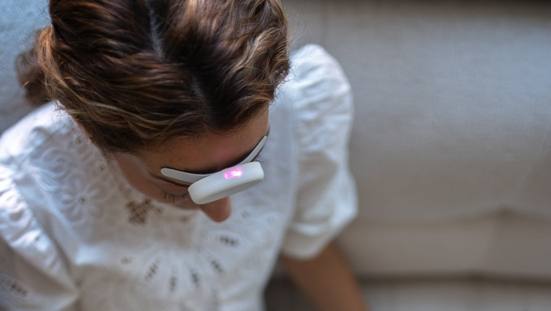 Mujer usando Relivia, dispositivo e-TNS para la migraña, con luz rosada en la frente